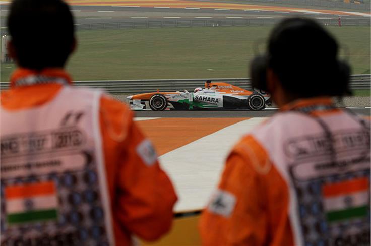Marshals look on as a Force India VJM06 passes by.