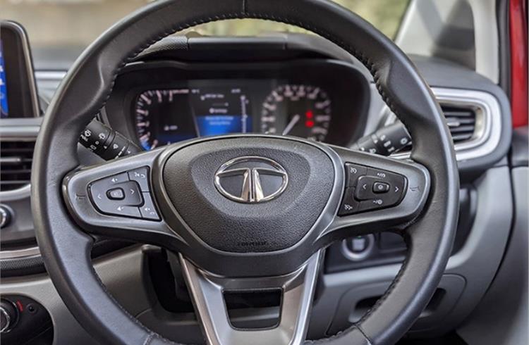 Communicative leather-wrapped steering wheel, horn pad extends outwards.