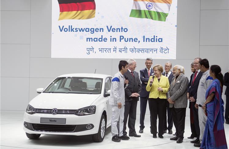 Prime minister Modi and chancellor Merkel speak to a young Indian apprentice who is training at VW India's Chakan plant.