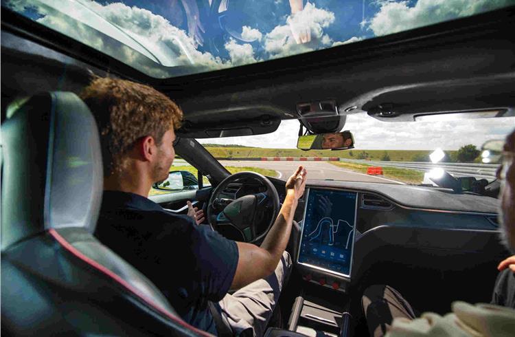 A test driver removes his hands from the steering wheel of a Tesla Motors Model S.