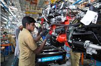 Preparing the engine with wiring and power steering pumps before lowering onto the frame. Engine is fitted with power steering drive.