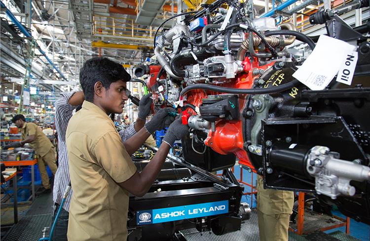 Preparing the engine with wiring and power steering pumps before lowering onto the frame. Engine is fitted with power steering drive.